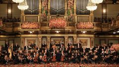 Imagen de la orquesta con el escenario engalanado con flores. 