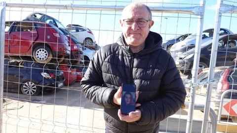 Ernesto posa con la foto de su sobrina delante de un cementerio de coches retirados de las calles.