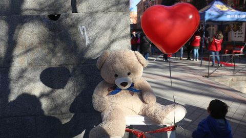 Un nio mira a un oso de peluche con un globo en las conocidas como colas del hambre de la plaza de San Amaro de Madrid