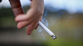 Una persona sosteniendo un cigarrillo.