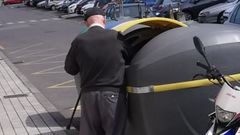 Un hombre levanta con el hombro la tapa de un contenedor