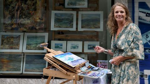 La pitora Hedi Ploegstra retratada pintando ante una exposici&oacute;n de sus cuadros en Vigo
