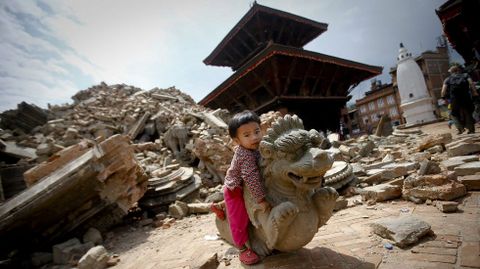 Una niña juega con una estatua caída en la plaza de Bhaktapur, en Katmandú, uno de los palacios reales situados frente a las tres plazas Durbar.