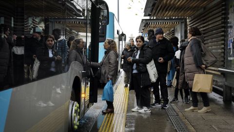 Unha cola de pasajeros para subir a un bus interurbano en la parada de los Jardines de M�ndez N��ez en A Coru�a