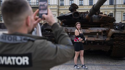 Una joven ucraniana posa ante un tanque ruso destrozado, en Kiev