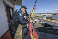 Un polic�a local coloca un cresp�n negro en la bandera espa�ola, que qued� izada a media asta. 