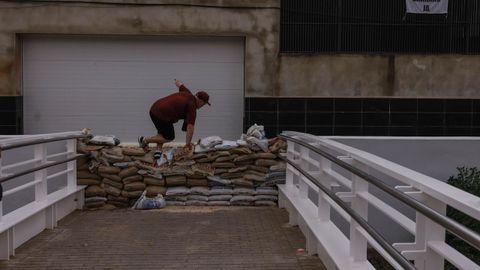 Un hombre salta los sacos de arena instalados para prevenir el desbordamiento del barranco de La Saleta, en Aldaia (Valencia)