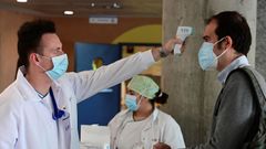 Un sanitario mide la temperatura a un hombre que accede al hospital de Alcorc�n, en Madrid