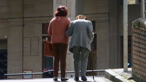 Una se�ora mayor sale a la calle acompa�ada de su cuidadora