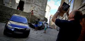 Turistas fotografiando ayer la iglesia de Santiago, con coches aparcados por todo su per�metro. 