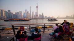 Gente tomando caf� en una terraza, con el �skyline� de Shangh�i al fondo.