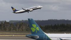 Un avi�n de Ryanair despega ante otro de Aer Lingus estacionado en el aeropuerto de Santiago-Rosal�a de Castro, en foto de archivo