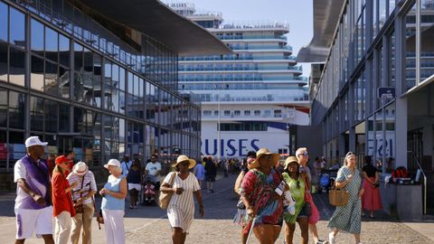 Cruceristas tras desembarcar en el puerto de A Coru�a, con un barco de la naviera Carnival al fondo, en una imagen de agosto de este a�o. 