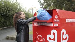 Una joven, metiendo una bolsa en un contenedor.