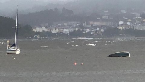 Un barco de vela ligera, que estaba fondeado, fue tumbado por el oleaje en Sada