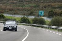 Un coche circula por la LU-546 entre Ribas Altas y A spera, con el trazado de la va rpida al fondo. 