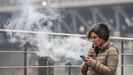 Imagen de archivo de una mujer con la nube de humo que sale al aspirar su vapeador