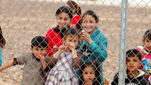 Varios nifos refugiados sirios observan a través de una valla en un campo de refugiados en Azraq, Jordania, el 29 de enero del 2018.