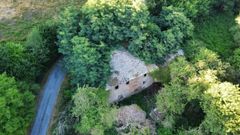 Vista area de una casa en una aldea de A Fonsagrada, tapada casi al completo por los rboles