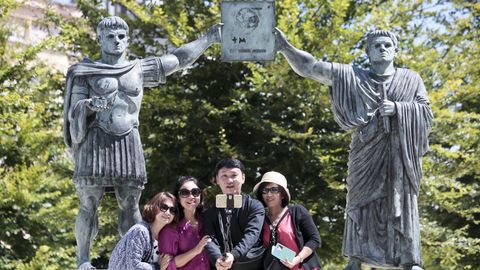 Un grupo de turistas posan ante la estatua en la que el emperador Csar Augusto entrega el legado a Pablo Fabio Mximo