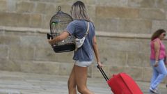 Una mujer camina con su maleta por la plaza del Obradoiro