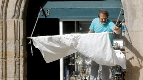 Un comerciante de la plaza de Prater�as de Santiago coloca un toldo para proteger su escaparate del calor