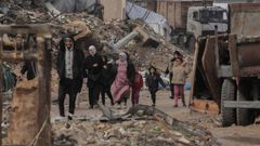 Una familia camina entre las ruinas de edificios bombardeados en Gaza