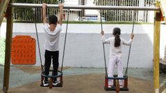Dos niños juegan en unos columpios de un parque infantil en A Coruña.