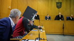 El acusado iraqu Taha A. J. cubrindose el rostro con una carpeta antes de saber hoy el veredicto en el Tribunal Regional Superior de Frankfurt.