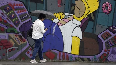 Una mujer se protege de la lluvia en Lugones