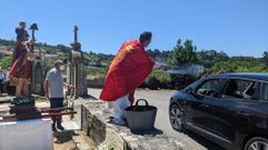 El cura de Campo Lameiro bendice a los coches con un cubo y una xesta durante la procesi�n de San Crist�bal