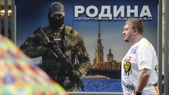 Un hombre camina ante un cartel con un soldado ruso en San Petersburgo
