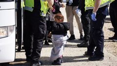 Una ni�a rescatada tras cruzar en barco el canal de la Mancha espera ser trasladada en una playa de la ciudad brit�nica de Kent.