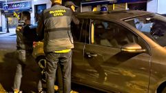 La Guardia Civil introduce en un coche policial a uno de los detenidos.