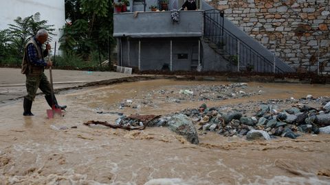 Un hombre trata de limpiar una calle en la ciudad de Volos, en Grecia.