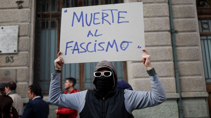 Una persona sostiene un cartel antifascista en un acto por 53 aniversario del golpe de Pinochet en Chile.