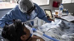 Un m�dico con equipo de protecci�n personal sostiene un tel�fono celular para permitir que un paciente con coronavirus realice una videollamada en el Hospital �ngeles Ciudad Ju�rez, en Chihuahua, M�xico