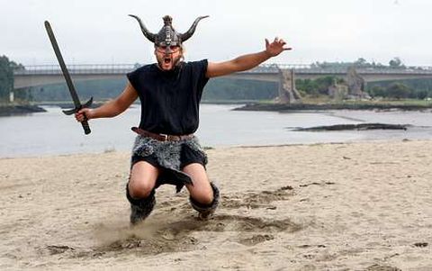 Ismael invadiendo la playa fluvial de Catoira ataviado con ropas vikingas mientras prepara su espada ante un posible ataque.