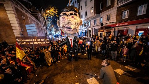Varios manifestantes golpean un muñeco que simboliza a Pedro Sánchez en las inmediaciones de la sede del PSOE nacional en Madrid.