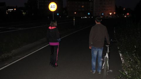 Peatones, de noche, por una de las v�as de servicio de la ronda