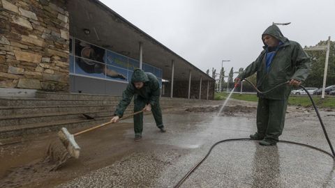 Los operarios limpiaron ayer el agua embarrada que se acumuló delante de las piscinas de Sar, que están cerradas por averías en la maquinaria