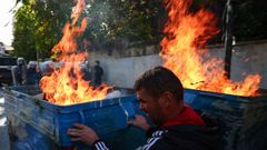 Un manifestante tras un contenedor ardiendo y ante la polic�a en Tirana
