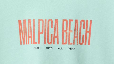 &laquo;Playa de Malpica, d&iacute;as de surf durante todo el a&ntilde;o&raquo;, reza la prenda en su parte delantera.