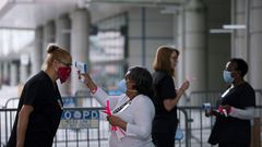 Personal médico toma la temperatura durante la preparacion del centro de convenciones Ernest N. Morial para pacientes de coronavirus, en Nueva Orleáns
