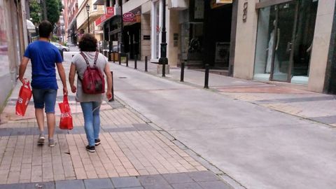 Bolsas pl�stico compras rebajas oviedo.Dos transe�ntes, durante el primer domingo de rebajas, portan sus compras en bolsas de pl�stico a pesar de su cobro