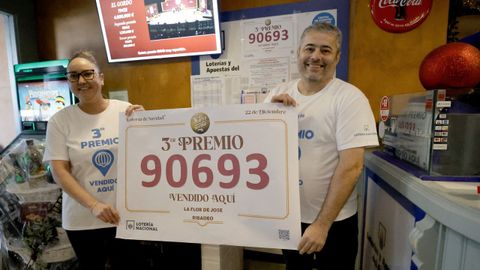 Jos&eacute; Fern&aacute;ndez, propietario del bar La Flor de Jos&eacute;, y su empleada Patricia P&eacute;rez sostienen el cartel con el n&uacute;mero 90.693, tercer premio de la loter&iacute;a de Navidad del que vendieron un d&eacute;cimo. 