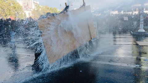 Estudiantes ayer en Par�s resistiendo el chorro del ca��n de agua de la polic�a.