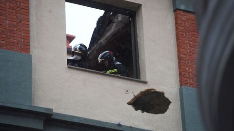 Unos bomberos lanzan escombros por una ventana prxima a la azotea del colegio San Vicente Pal