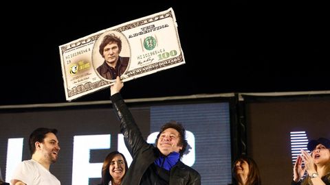 Milei eleva un billete de cien d�lares con su cara, en una imagen de archivo.