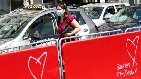 Una mujer con mascarilla pasa por delante de un anuncio del 26 Festival de Cine de Sarajevo, Bosnia Hezergovina